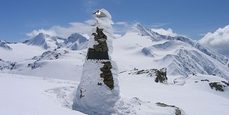 Ein dreieckiges Denkmal mit Steinen in einer Gletscherlandschaft. 