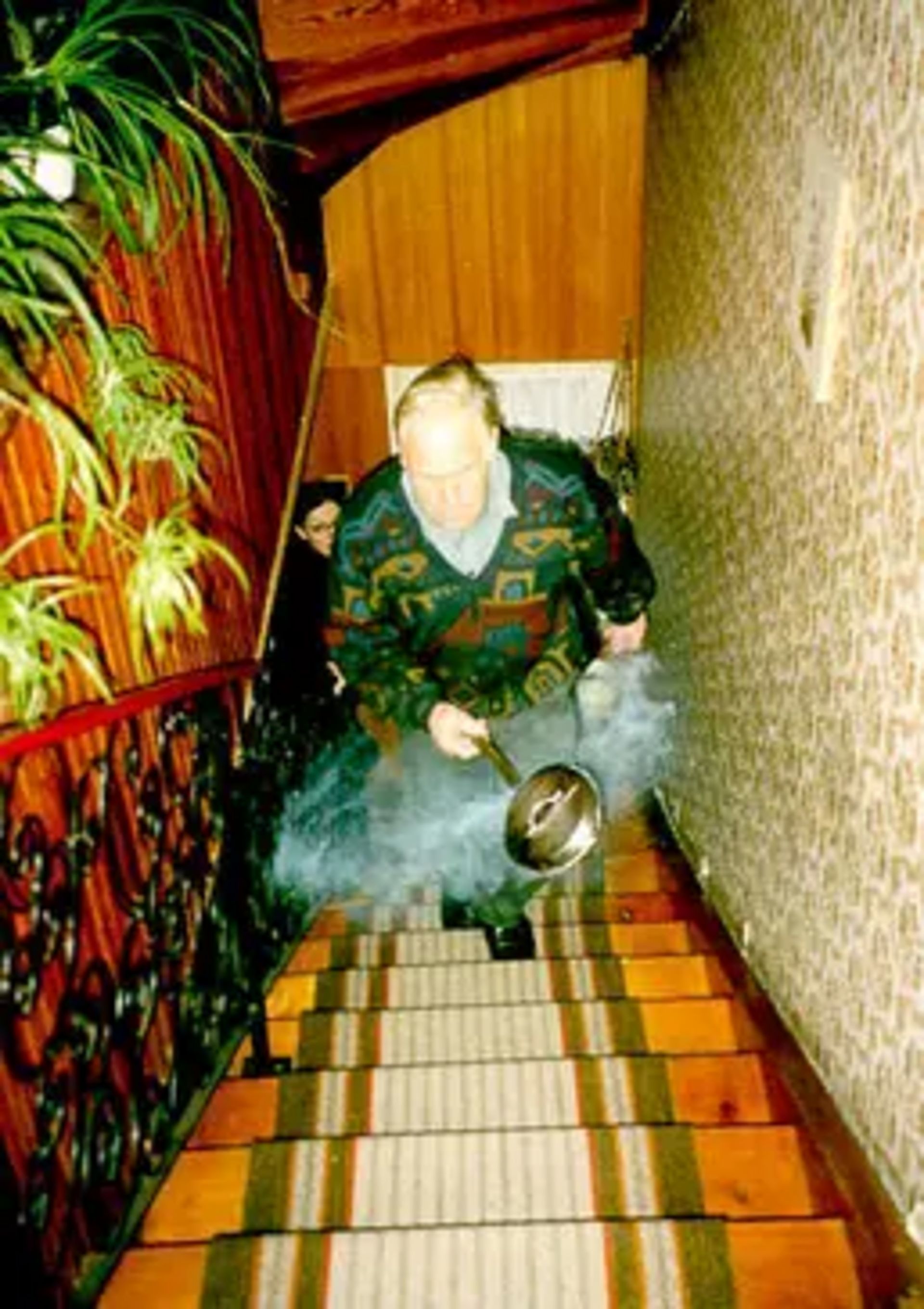 Un uomo sale le scale durante l'incensamento della casa. 
