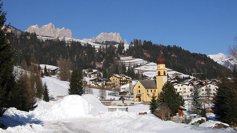 Winterpanorama von Soraga di Fassa mit der Kirche der Heiligen Peter und Paul