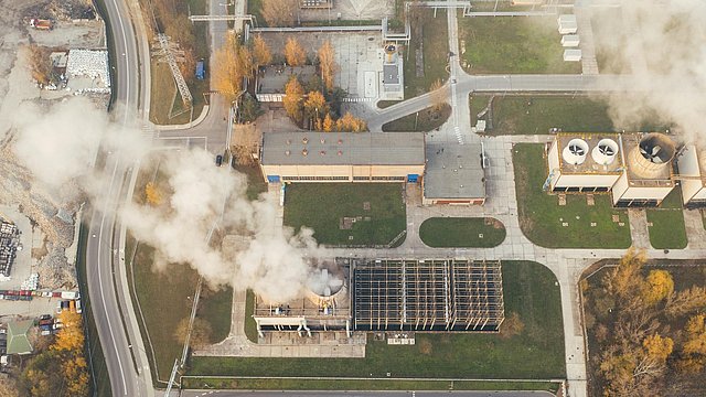 Bild einer Landschaft von oben, in der man ein Gebäude sieht, aus dem weißer Rauch aufsteigt.