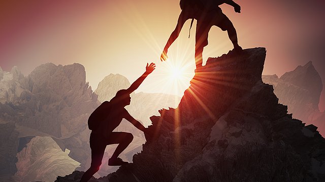 Mann hilft anderem auf einen Berggipfel