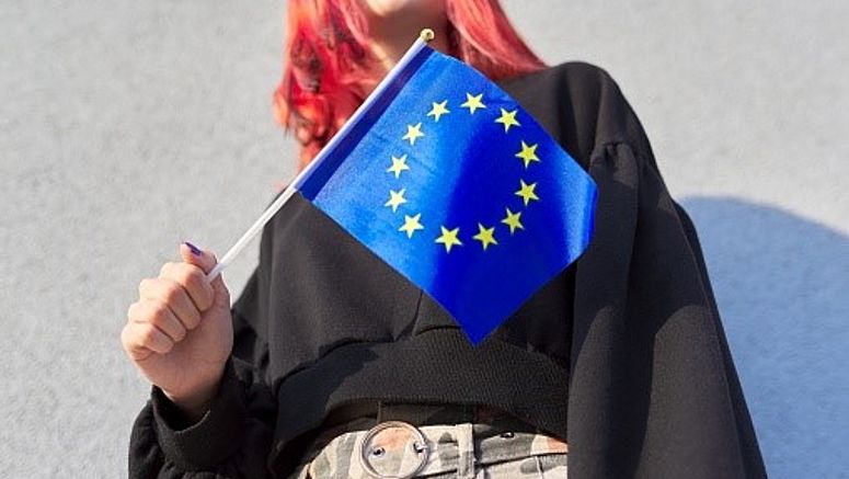 Ragazza che tiene in mano una bandierina dell’Unione Europea.