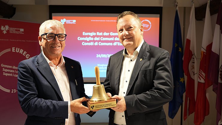 Consegna simbolica della campana delle riunioni nel Consiglio dei Comuni dell'Euregio: (a sinistra) il presidente in carica Andreas Schatzer (Alto Adige) e il suo successore Karl-Josef Schubert