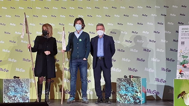 Claudio Martinelli consegna il bastone dell'Anno dei Musei dell'Euregio alla vicepresidente del Muse Laura Strada. Con loro anche il ricercatore Alessandro de Bertolini