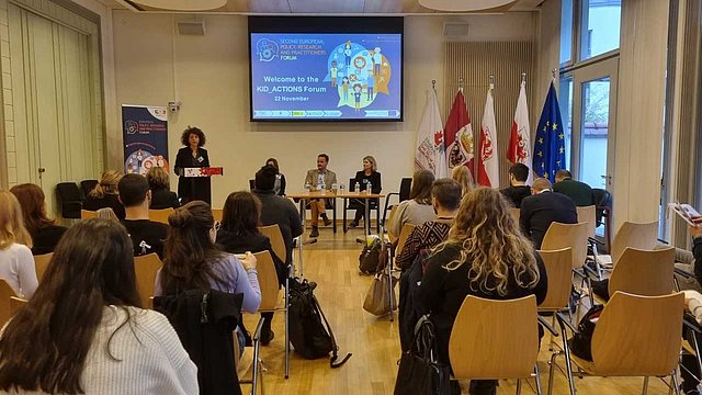 Konferenzraum mit Publikum und Diskussionsteilnehmern