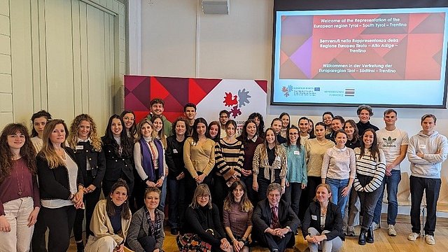 Die Gruppe von Studierenden der Uni Bozen steht vor dem Banner der Europaregion Tirol-Südtirol-Trentino.