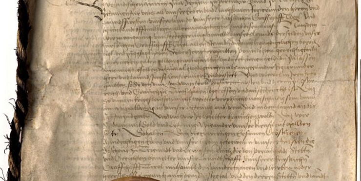 Un documento storico medievale con al fronte un sigillo rosso. 
