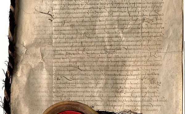 Un documento storico medievale con al fronte un sigillo rosso. 