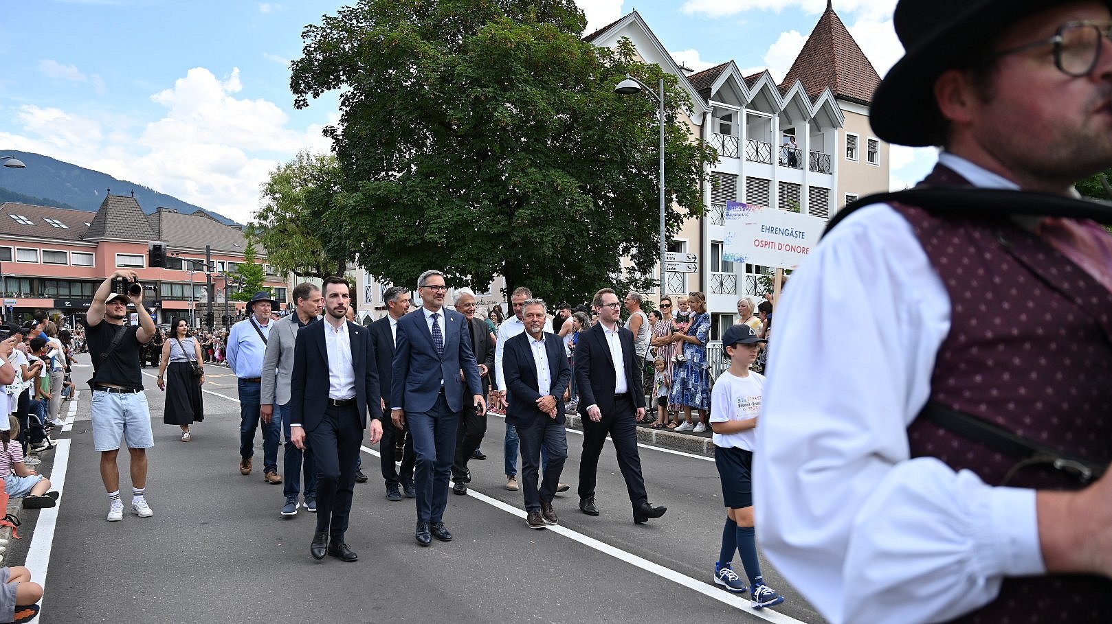 © Associazione Brunico Plan de Corones Turismo/Gianvito Coco Sfilata con (1a fila da sinistra) l'assessore provinciale Simone Marchiori (Trentino), il presidente dell'Euregio Arno Kompatscher (Alto Adige), il sindaco di Brunico Bruno Wolf e il vicepresidente Philip Wohlgemuth (Tirolo).