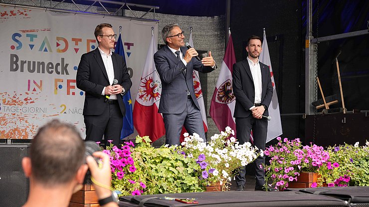 Dialogo politico sull'Euregio sul palco della festa a Brunico con (da sinistra) i rappresentanti della Giunta dell'Euregio Philip Wohlgemuth (Tirolo), il presidente dell'Euregio Arno Kompatscher (Alto Adige) e Simone Marchiori (Trentino).
