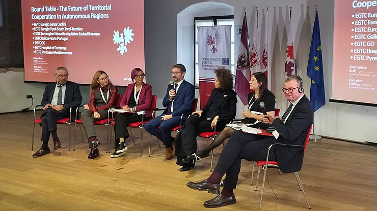 © Euregio/Armin Gluderer Runder Tisch mit den EVTZ-Direktorinnen und Direktoren: (von links) Xavier Conill (Cerdanya), Aldara Vázquez Rodriguez (Galicia-Norte Portugal), Romina Kocina (GO), Xavier Bernard Sans (Pyrenees-Mediterranean), Elisa Bertò (Tirol-Südtirol-Trentino) Leyre Azcona Sanz de Galdeano (Nouvelle-Aquitaine Euskadi Navarra) und Moderator Jens Woelk (Universität Trient)