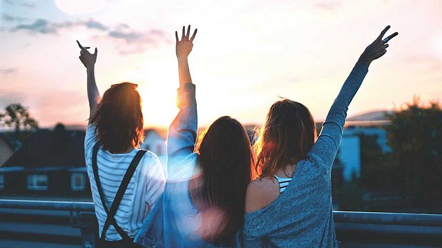 © Unsplash/Simon Maage Junge Reisende umarmen sich bei Sonnenuntergang.