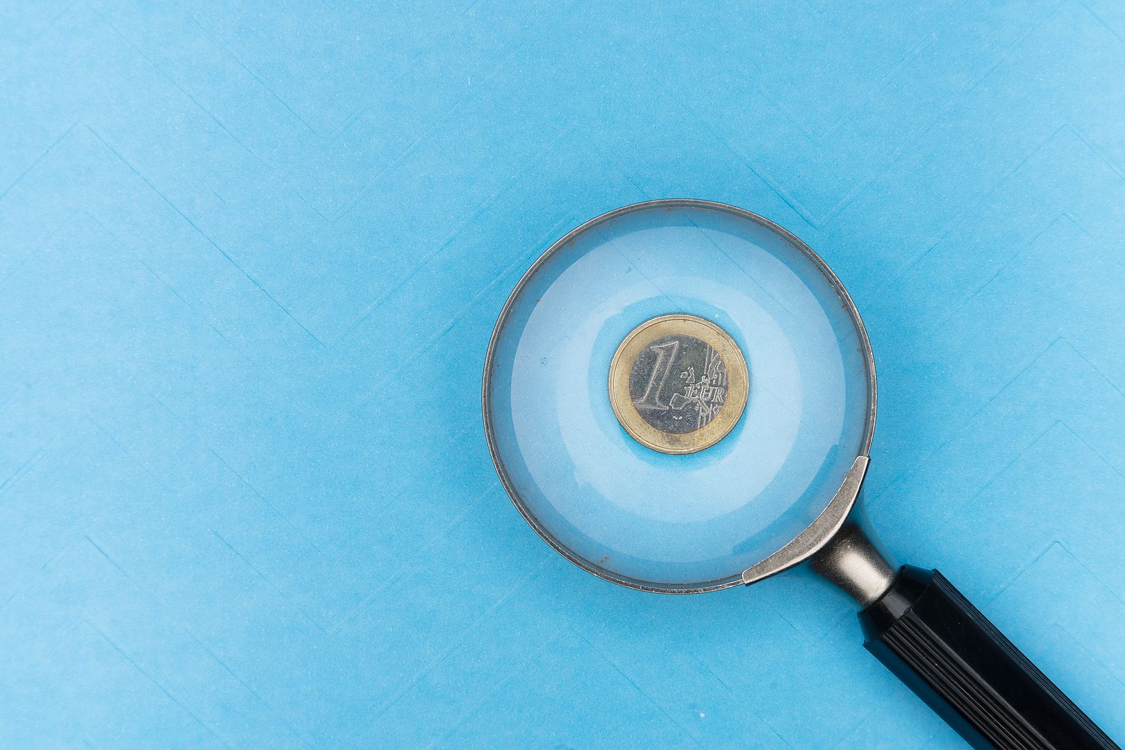 Magnifying glass pointing to a euro coin