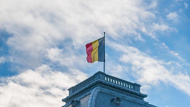 Historisches Gebäude mit der belgischen Flagge an der Spitze.