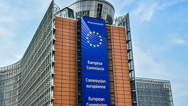 Edificio della Commissione europea con appeso sulla facciata uno striscione con il nome della Commissione in diverse lingue.