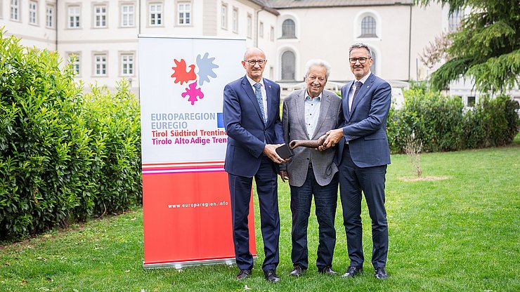 I presidenti Anton Mattle (Tirolo, a sinistra) e Arno Kompatscher (Alto Adige, a destra) con il fondatore, l'ex presidente del Tirolo Wendelin Weingartner, e il premio, una scultura dell'artista Lois Anvidalfarei. 