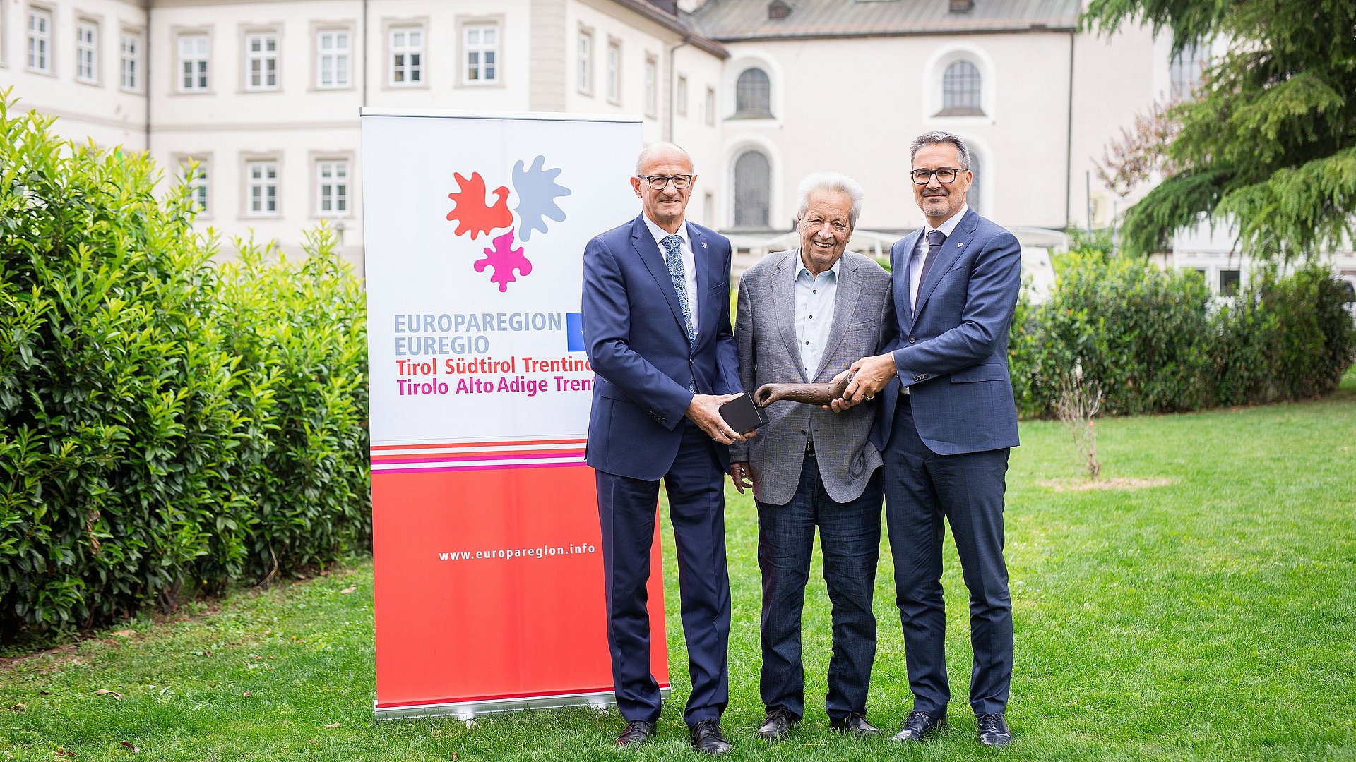 © Journalismusfest/Alena Klinger) Die Landeshauptleute Anton Mattle (Tirol, links) und Arno Kompatscher (Südtirol, rechts) mit dem Stifter, dem Tiroler Landeshauptmann a. D. Wendelin Weingartner und dem Preis, einer Skulptur des Künstlers Lois Anvidalfarei.