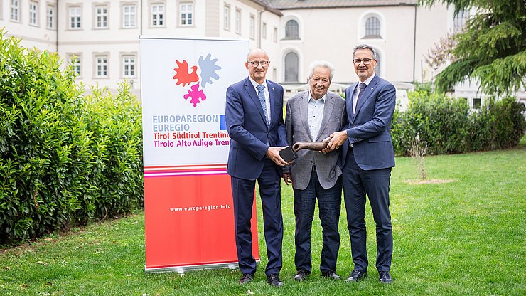 Die Landeshauptleute Anton Mattle (Tirol, links) und Arno Kompatscher (Südtirol, rechts) mit dem Stifter, dem Tiroler Landeshauptmann a. D. Wendelin Weingartner und dem Preis, einer Skulptur des Künstlers Lois Anvidalfarei. 