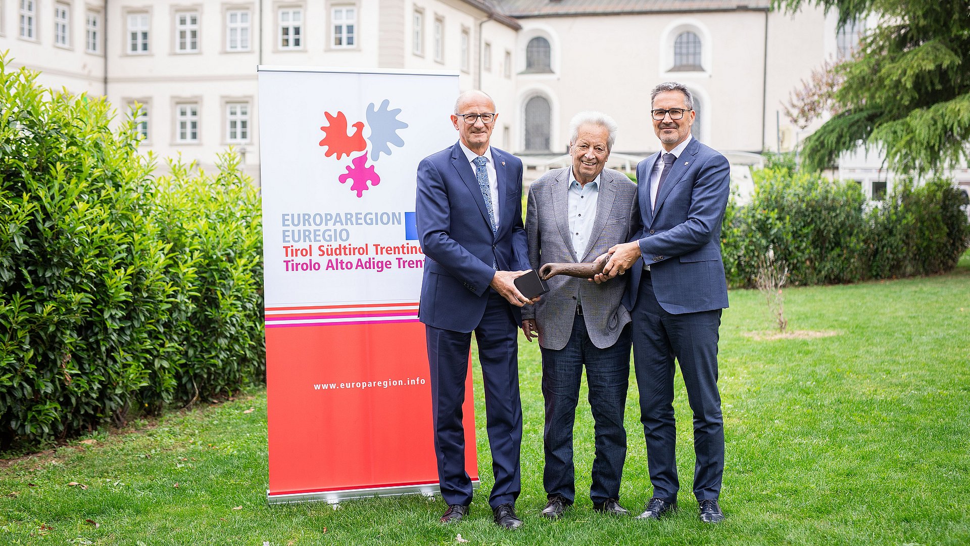 Die Landeshauptleute Anton Mattle (Tirol, links) und Arno Kompatscher (Südtirol, rechts) mit dem Stifter, dem Tiroler Landeshauptmann a. D. Wendelin Weingartner und dem Preis, einer Skulptur des Künstlers Lois Anvidalfarei. 
