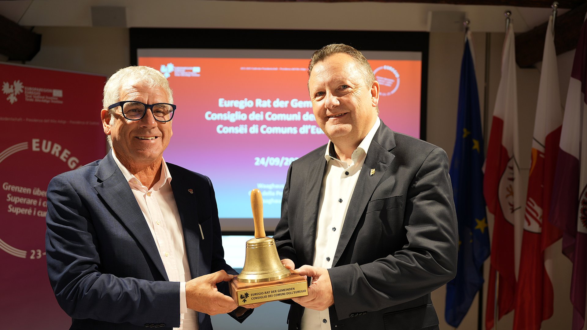 Symbolic handover of the session bell at the Euregio Council of Municipalities: (left) the incumbent President, Andreas Schatzer (South Tyrol), and his successor, Karl-Josef Schubert (Tyrol)