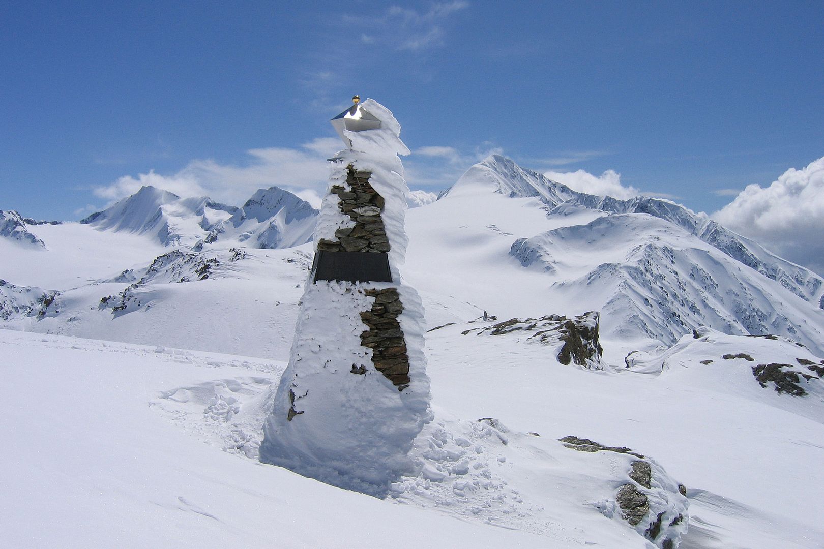 Ein dreieckiges Denkmal mit Steinen in einer Gletscherlandschaft. 