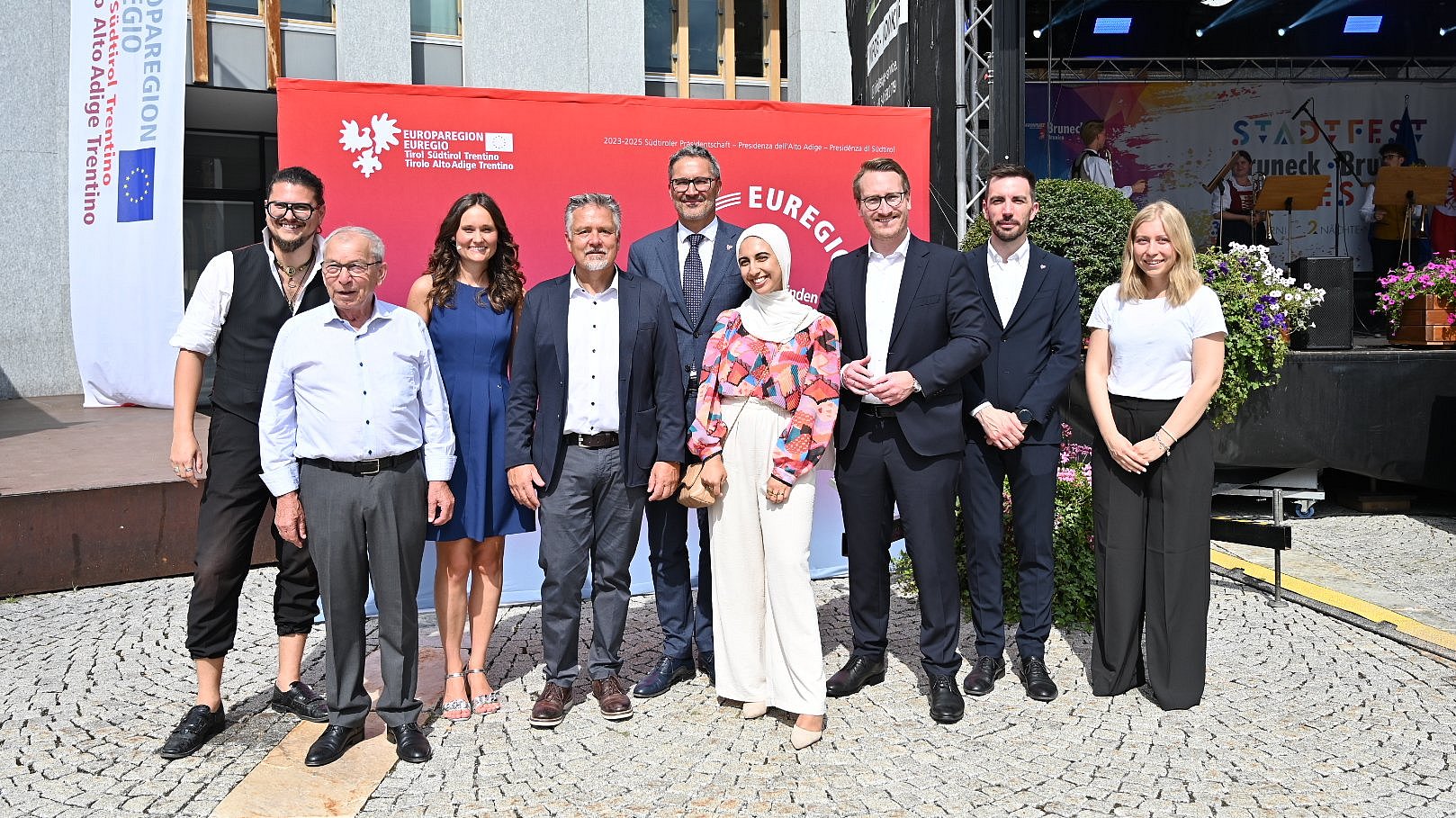 © Associazione Brunico Plan de Corones Turismo/Gianvito Coco In piedi al dialogo sull'Euregio (da sinistra) Simon Mariacher, Josef Urthaler, la moderatrice Nicole Abler, il sindaco Bruno Wolf, il presidente dell'Euregio Arno Kompatscher (Alto Adige), Assia Brahimi, il vicepresidente Philip Wohlgemuth (Tirolo), l'assessore provinciale Simone Marchiori (Trentino), Celina Moser.