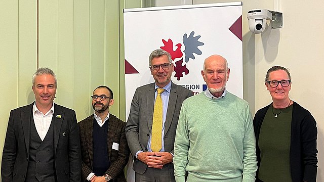 Das Foto zeigt die Rednerinnen und Redner, die die Eröffnungsbeiträge der Veranstaltung gehalten haben, in einer Reihe nebeneinander positioniert, vor dem Logo der Vertretung der Europäischen Region Tirol – Südtirol – Trentino.