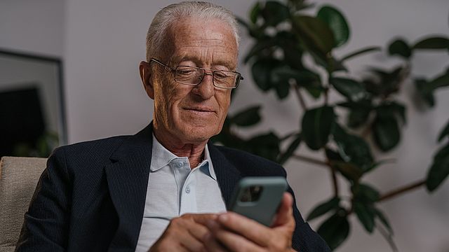 Ein älterer Herr, der ein Smartphone bedient.