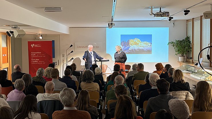 I lingac sön i fostüs leterars de Karl Felix Wolff: la prof. Ulrike Kindl (a man ciampa) y la vizedireturia dl Istitut dl Archif dl Prener Ursula A. Schneider cun le massif dl Ciadenac iadedô.    