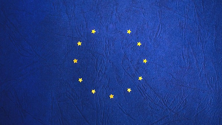 Zwölf goldene Sterne bilden einen Kreis auf einem tiefblauen Hintergrund und symbolisieren die Einheit und Harmonie der Europäischen Union.