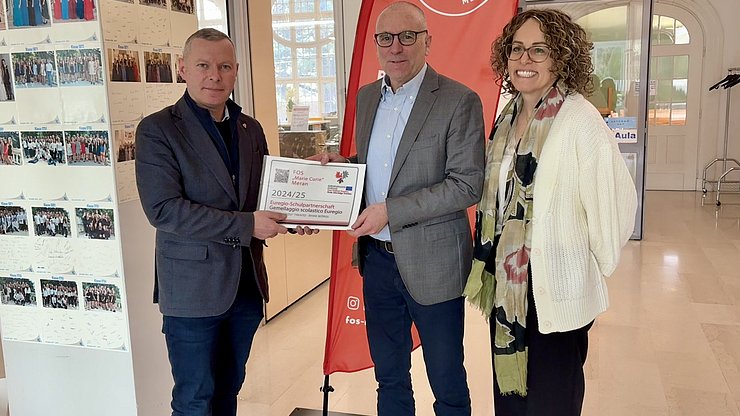 Il Segretario Generale dell'Euregio Christoph von Ach (sx) consegna a Merano la targhetta di riconoscimento “Gemellaggio scolastico Euregio” al Direttore dell'Istituto FOS Markus Dapunt e all'insegnante Barbara Pircher