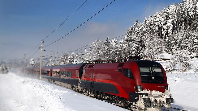 Railjet in schneebedeckter Winterlandschaft.