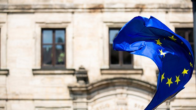 Die EU-Flagge weht vor einem Palast im Hintergrund.